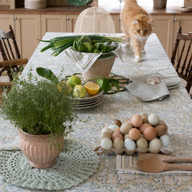 Dante bordsduk på ett vårdukat bord med grönsaker, citroner, ägg och gröna växter