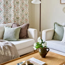 Glasgow ullpläd med fransar draperad över en ljus soffa i ett ombonat vardagsrum