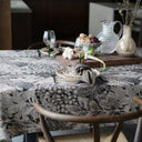 Mönstrad bordsduk med stora blad på ett elegant dukat matbord med porslin, glas och vaser