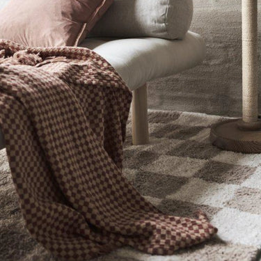 Rutig Nefelli bomullspläd i rost och beige på en soffa
