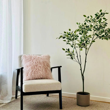 Rosa kuddfodral 45x45 i fluffig akryl med mjuk textur på en fåtölj
