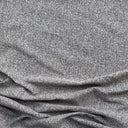 Närbild på möbeltyget Alex i 100 % polyester med diskret vävd struktur i beigegrå toner, visat med mjukt fall som framhäver tygets naturliga känsla och slitstyrka.