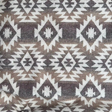 Aspen tyg med geometriskt mönster i beige, brunt och naturvitt, perfekt för plädar, prydnadskuddar och rustik inredning.