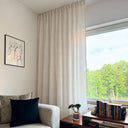 Faye skir måttsydd gardin i ljus linnefärgad med mjukt fall framför stort fönster i vardagsrum.