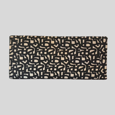 Letters väggmonterad sänggavel sedd framifrån med rektangulär form, rundade hörn och abstrakt grafiskt mönster i svart och beige.