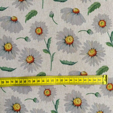 Närbild av tyget Daisy som visar prästkragemönstret, linnelooken och mönstrets skala med hjälp av ett måttband.