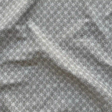Närbild av möbeltyget Ines som visar den dubbelvävda strukturen, den kraftiga kvaliteten och det diskreta geometriska mönstret i grå toner.