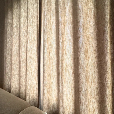 Beige Nova gardin som filtrerar dagsljuset och visar tygets vävda struktur och mjuka fall.