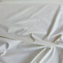 Offwhite bomullsflanell draperad i mjuka veck som visar tygets följsamma struktur och mjuka känsla