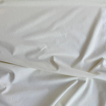 Offwhite bomullsflanell draperad i mjuka veck som visar tygets följsamma struktur och mjuka känsla