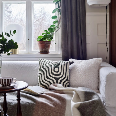 Grönrandig Quinn pläd med fransar draperad över en säng i ett ombonat sovrum