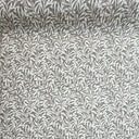 Närbild av Ramas beige vaxduk med tätt slingrande bladmönster och textilliknande struktur.
