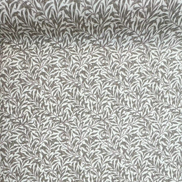 Närbild av Ramas beige vaxduk med tätt slingrande bladmönster och textilliknande struktur.