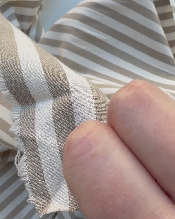 Video där en hand visar mjukt och följsamt randigt bomullstyg i naturbeige och grön