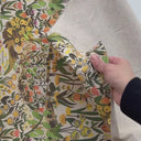 Hand som känner på färgstarkt möbeltyg med blommigt mönster och naturstruktur
