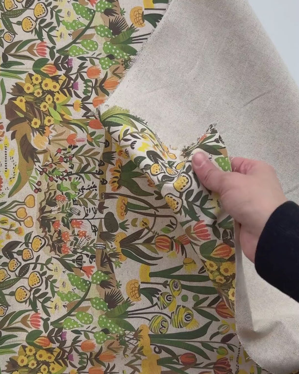 Hand som känner på färgstarkt möbeltyg med blommigt mönster och naturstruktur