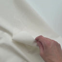 En hand visar den mjuka, textilliknande ytan på den offwhite linnelook-vaxduken.